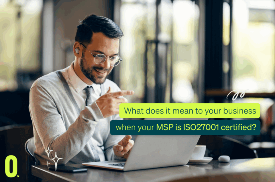 A smiling man in glasses joins a secure video call on his laptop in a modern café. Text: How does ISO27001 MSP boost your cyber security?.